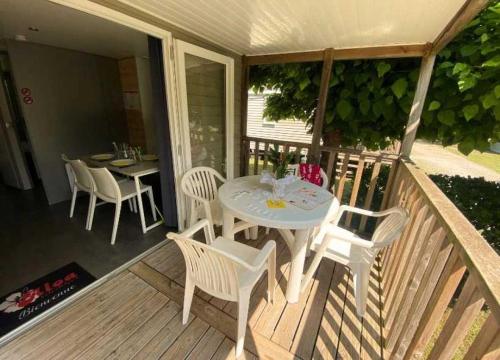 une table et des chaises blanches sur une terrasse en bois dans l'établissement Camping - Piscine - ccaghc0, à Hourtin