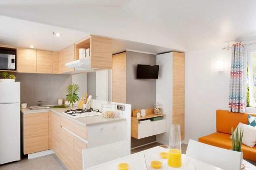 Il comprend une cuisine équipée d'une cuisinière et d'un réfrigérateur blanc. dans l'établissement Camping - Parc aquatique - ccahfai, à Argelès-sur-Mer