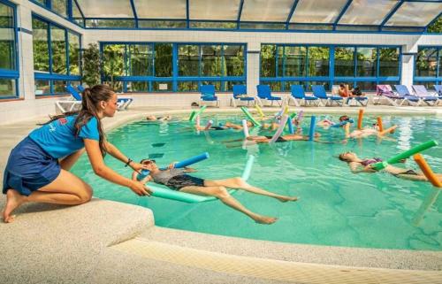 a woman in a pool with a group of people in the water at ZEcamping familial espace aquatique pet friendly in Argelès-sur-Mer