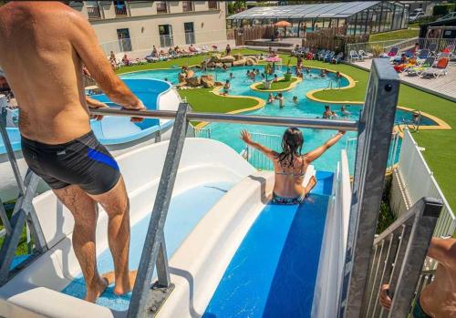 a man and a woman riding a water slide at a resort at ZEcamping 4 familial espace aquatique pet friendly in Ambon