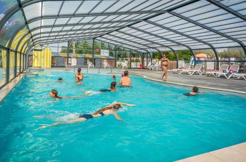 a group of people swimming in a swimming pool at ZEcamping 4 familial espace aquatique pet friendly in Ambon