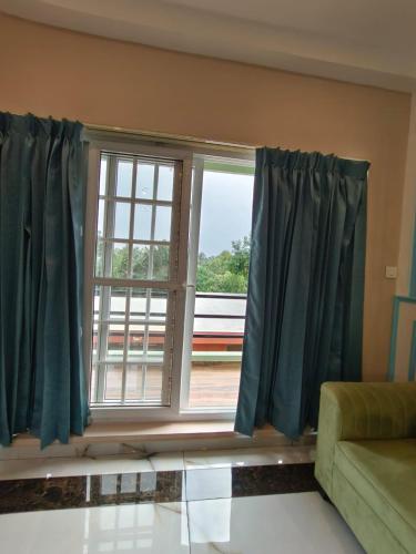 a living room with a window with blue curtains at Le French Nest in Puducherry