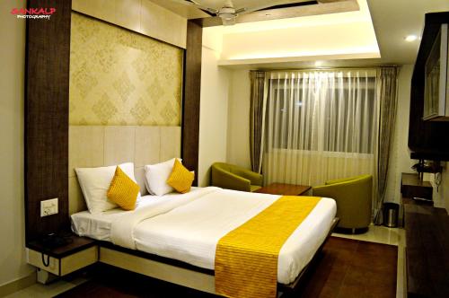 a hotel room with a large bed with yellow pillows at Sepoy Grande Mysore in Mysore