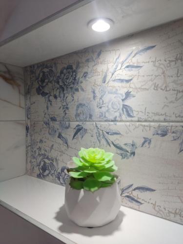 a white vase sitting on a counter with a plant in it at Ticina apartment in Sarajevo