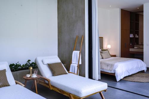 a room with two beds and two chairs and a mirror at Villa Mamakami - Private Luxury Rooms in Canggu in Canggu
