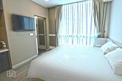 a bedroom with a white bed and a large window at Legacy Hotel Ipoh in Ipoh