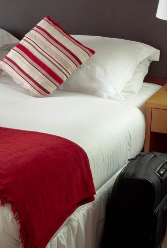 a bed with a red blanket and a black suitcase at Ellan Vannin Hotel in Douglas