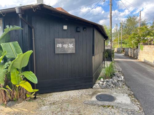 a black building with a sign on the side of it at 檸檬草ー奄美の自然の香る宿ー in Amami