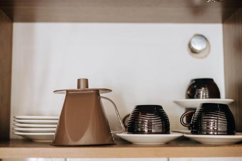 a tea kettle on a shelf with plates and bowls at Residencial Mizinho Ap2 in Florianópolis
