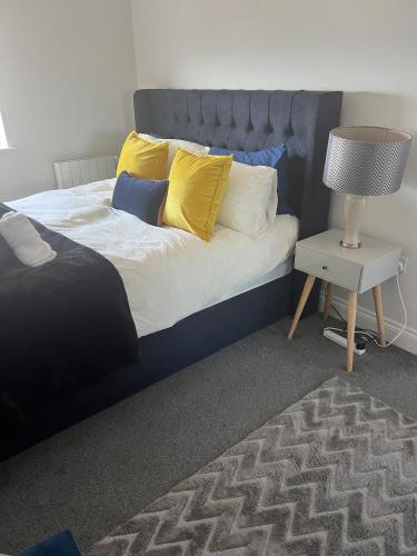 a bed with yellow pillows and a table with a lamp at Chesil Beach View in Fortuneswell