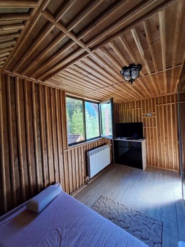a bedroom with a bed in a room with wooden walls at Cabana cu trofee in Schitu-Tarcău