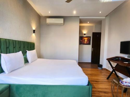 a bedroom with a white bed and a green couch at Hotel City Premier - Golf Course Road ,Gurgaon in Gurgaon