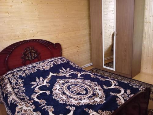 a bed with a blue and white quilt on it at Chilegir Host in Çilǝgir