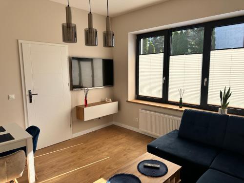 a living room with a black couch and two windows at Apartamenty Na Krasnym in Supraśl