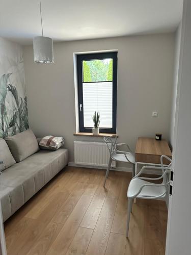 a living room with a couch and a table and a window at Apartamenty Na Krasnym in Supraśl