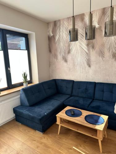 a living room with a blue couch and a coffee table at Apartamenty Na Krasnym in Supraśl