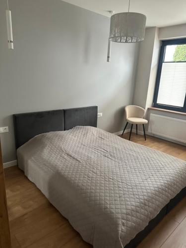a bedroom with a bed and a chair and a window at Apartamenty Na Krasnym in Supraśl