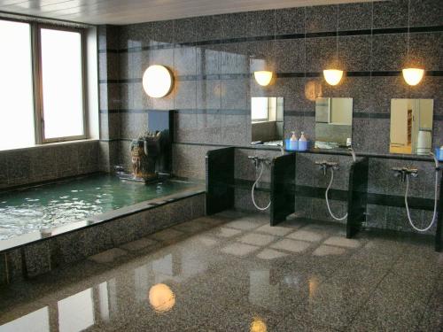 a bathroom with two sinks and a pool of water at Hotel Sunroute Goshogawara in Goshogawara