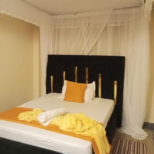 1 Schlafzimmer mit 2 Betten und gelber Bettwäsche in der Unterkunft Eldorado cabin in Nyeri