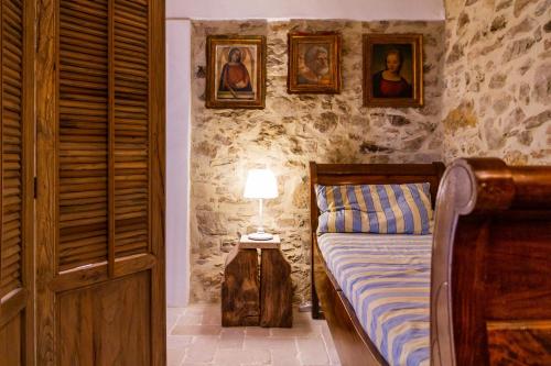 a bedroom with a bed and portraits on the wall at Casa Pereta in Magliano in Toscana