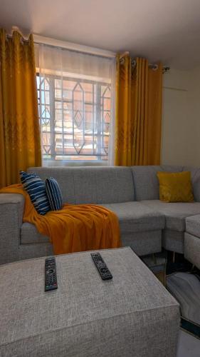 ein Wohnzimmer mit einem Sofa und zwei Fernbedienung in der Unterkunft Eldorado cabin in Nyeri