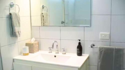 Un baño blanco con lavabo y espejo. en Sawtell Sunrise, en Sawtell