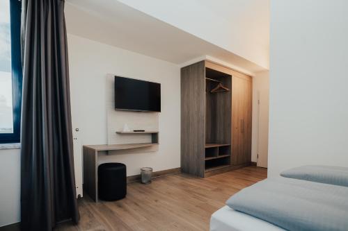 a bedroom with a bed and a desk with a television at Lechpark Hotel in Untermeitingen