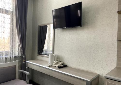 a hotel room with a phone and a tv on the wall at Diyor Hotel in Margilan