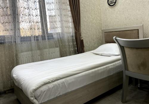 a bedroom with a bed and a window and a chair at Diyor Hotel in Margilan