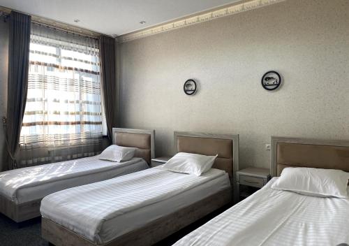 a room with two beds and a window at Diyor Hotel in Margilan