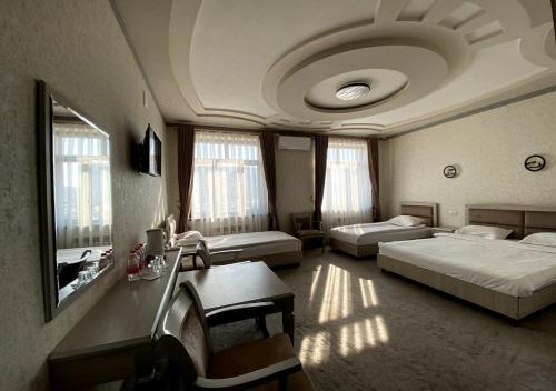 a hotel room with two beds and a table and a desk at Diyor Hotel in Margilan