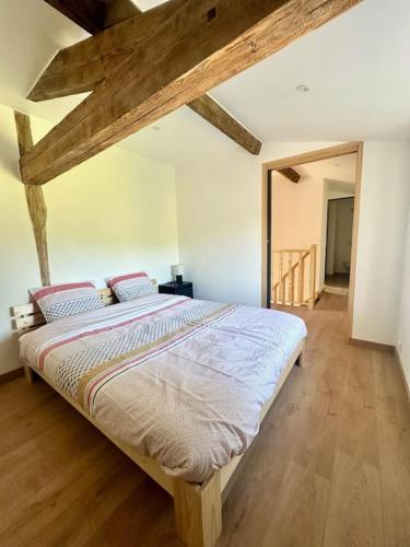 une chambre avec un grand lit dans une pièce avec des plafonds en bois dans l'établissement L acheneau, à Cheix-en-Retz