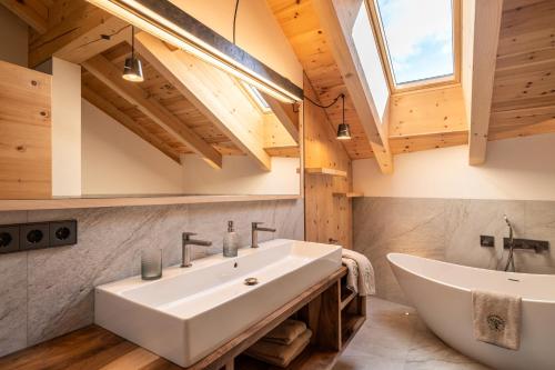 a bathroom with a large white sink and a tub at Großplonerhof in Luson