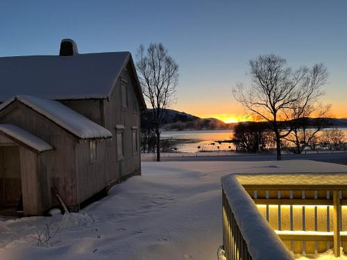 a barn in the snow with the sunset in the background at Nordlands hytta in Meby