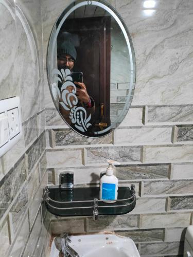 a man taking a picture of a mirror in a bathroom at Shraddhalu Niwas in Prayagraj