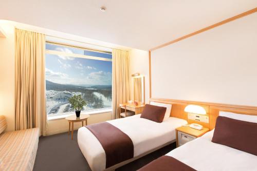 Rockwood Hotel & Spa في Ajigasawa: غرفة فندقية بسريرين ونافذة كبيرة