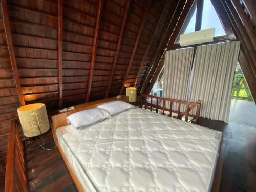 a bed in a room with a large window at Wira's TB Villas, One Bedroom Wooden Pool Villa in Kapal