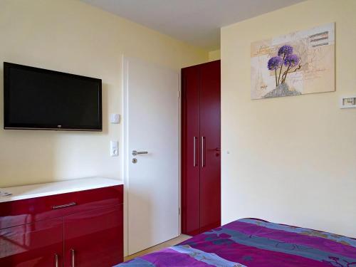 グロヴェにあるUrlaub Mit Hund Im Bernsteinhusのベッドルーム(赤いキャビネット、薄型テレビ付)