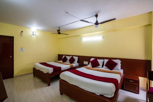 two beds in a room with yellow walls at Hotel Vyshak residency in Mysore
