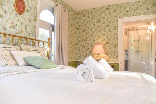 - une chambre avec un grand lit blanc et du papier peint floral dans l'établissement Les Trois Moulins - 10min Pont L'Evêque - 10P, à Les Authieux-sur-Calonne