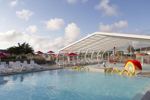 une piscine avec des chaises et un grand bâtiment dans l'établissement Domaine Résidentiel de Plein Air Les Paludiers, à Batz-sur-Mer