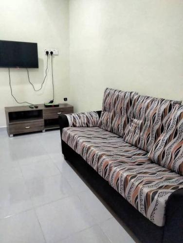 a couch in a living room with a television at My Guesthouse Bayas in Langkawi Intl