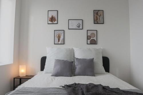une chambre avec un lit avec quatre tableaux au mur dans l'établissement Le carré, appartement de ville, à Mulhouse