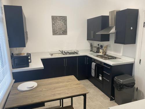 a kitchen with black cabinets and a wooden table at Comfortable Norton Studio in Stockton-on-Tees