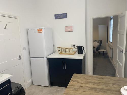 a kitchen with a white refrigerator and blue cabinets at Comfortable Norton Studio in Stockton-on-Tees