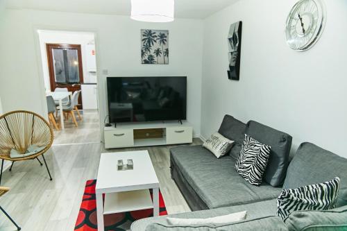 a living room with a couch and a tv at Emerald Haven 5 Star Proximity in London