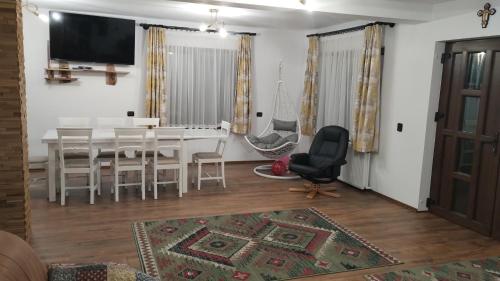 a dining room with a table and chairs and a television at Casa Noastră in Vidra