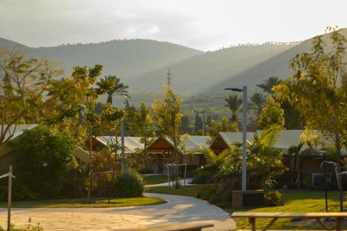 a park with trees and buildings and a mountain at Layla Glamping in Nir Dawid
