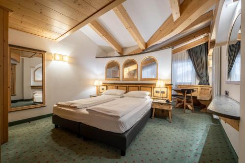 a bedroom with a bed and a desk in a room at Croce Bianca Leisure & Spa Hotel in Canazei