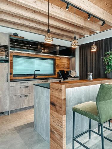 a kitchen with a bar with a green chair at ZSAM Chalets mit Sauna und Hottub in Garmisch-Partenkirchen